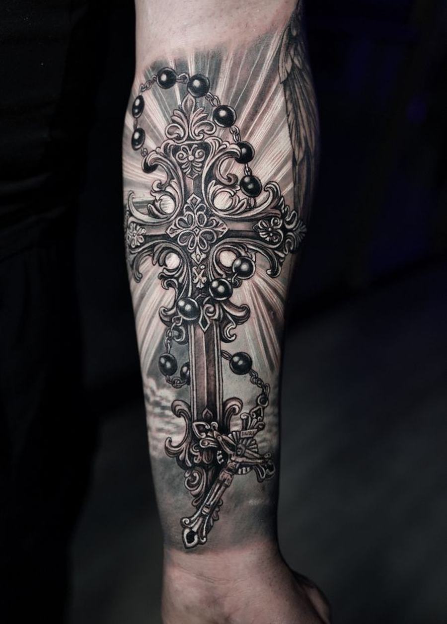 Black-and-gray realism forearm tattoo of an ornate cross with rosary beads, done at Las Olas Tattoo Shop